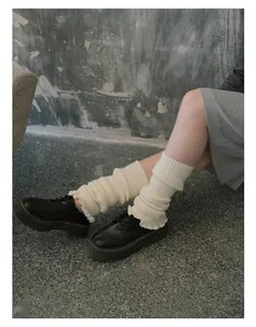 Detail of cream white cable knit leg warmers with ruffle trim and ribbed texture style