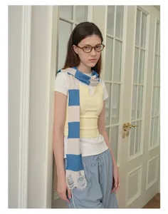 Detailed knit texture of blue striped wool blend scarf with fringe and distressed edges