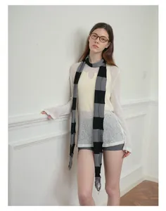 Close-up of black and grey striped knit scarf with frayed edge details on model