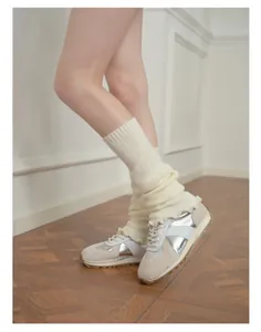 Detailed texture of off-white knitted leg warmers with ribbed ruffles and soft folds