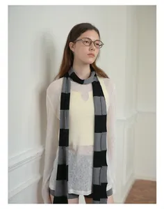 Detail of blue and grey striped wool blend scarf styled with a white knit top