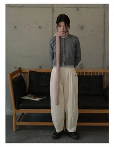 Chic women's fall outfit featuring a pink knit scarf and high-waist beige trousers