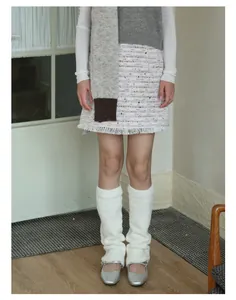 Dettaglio degli scaldamuscoli in peluche bianco con morbida trama in stile Y2K