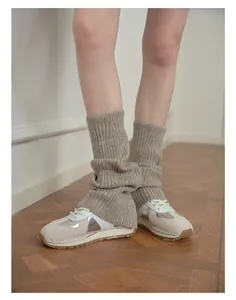 Close-up of soft wool blend knit leg warmers in oatmeal grey with ribbed texture