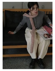 Detail view of pink speckled knit scarf paired with a grey cardigan and quilted trousers
