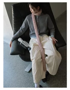 Chic long pink plush scarf styled with a grey-blue knit cardigan and quilted pants