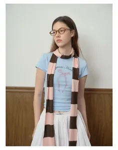 Detail view of blue striped wool blend scarf paired with a bow print cotton t-shirt