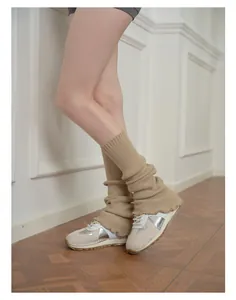 Detail of beige ribbed knit leg warmers with ruffle trim in a layered aesthetic