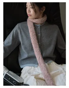 Detail view of a pink textured knit scarf styled with a grey button-up cardigan and white skirt