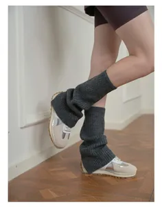 Detailed texture of charcoal grey ribbed knit leg warmers over stylish sneakers
