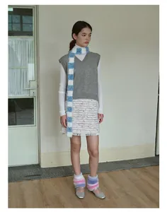 Detail of a sparkling blue and white striped long knit scarf styled with a winter outfit