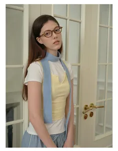 Detail shot of light blue knitted skinny scarf styled with a yellow ribbed tank top