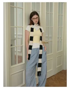 Detail of a distressed black and white striped knit scarf styled over a casual outfit