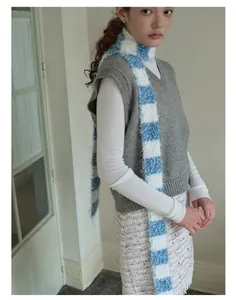 Detail of blue and white striped plush scarf styled with a grey V-neck knit vest