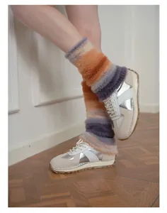 Dettaglio di scaldamuscoli in finta pelliccia sfumata con sneakers su parquet