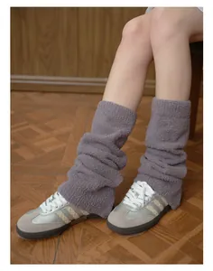Dettaglio di scaldamuscoli in peluche grigio con morbida trama a maglia e sneakers
