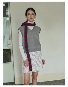 Dettaglio sciarpa in misto lana a righe rosse e blu con gilet in maglia grigio scuro
