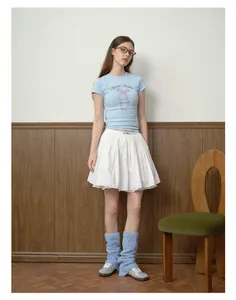 Dettaglio di scaldamuscoli in maglia blu soffice abbinati a sneakers e gonna a pieghe