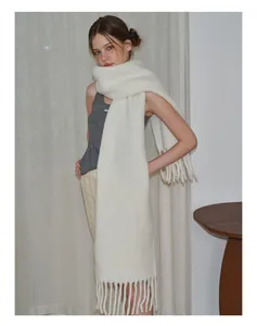 Detailaufnahme des cremeweißen Wollmischschals mit weichen Fransen und Strickstruktur