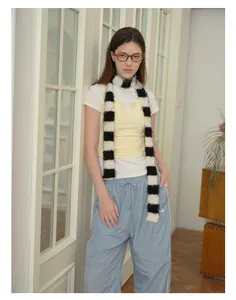 Detail of a fluffy black and white checkered plush scarf styled with a yellow vest