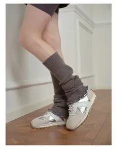 Close-up of dark grey knitted leg warmers with delicate ruffle edges and slouchy texture