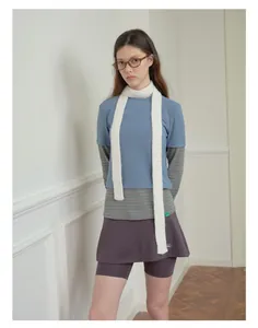 Dettaglio di una sottile sciarpa bianca a maglia abbinata a un outfit casual con occhiali