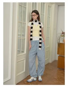 Detail shot of a long black and white striped fuzzy scarf in a retro sporty outfit