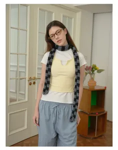 Dettaglio di una sciarpa in misto lana a righe abbinata a gilet giallo e pantaloni casual