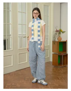 Detail of blue and white checkered fluffy scarf with yellow vest and blue cargo pants