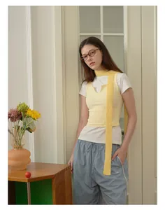 Dettaglio di una lunga sciarpa gialla in maglia di lana abbinata a un outfit casual