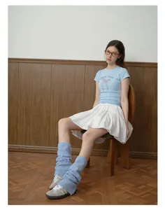 Dettaglio degli scaldamuscoli in maglia azzurra con gonna a pieghe bianca stile retrò