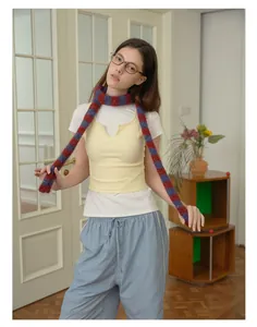 Dettaglio di sciarpa in lana a righe rosse e blu abbinata a gilet e pantaloni casual morbidi