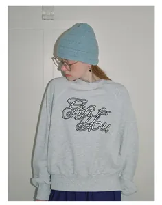 Close-up of light blue textured knit beanie paired with casual grey sweatshirt outfit