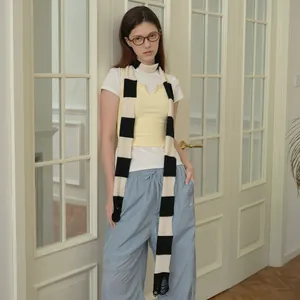 Stylishly layered blue striped wool blend knit scarf paired with a white tee and yellow vest