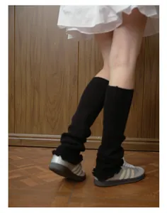 Detail of black knitted leg warmers with ruffle edge and balletcore style stacking