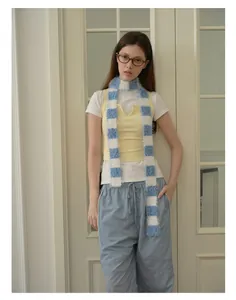Blue and white plaid plush scarf styled with a yellow vest and casual blue pants