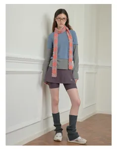 Close-up of stylish y2k knit outfit featuring a soft pink and orange checkered plush scarf