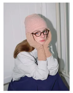 Detail of pink bouclé wool knit hat paired with long camel ribbed knit gloves for winter