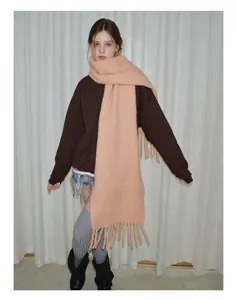 Nahaufnahme eines dicken pfirsichfarbenen Strickschals mit weichen Quasten und Textur