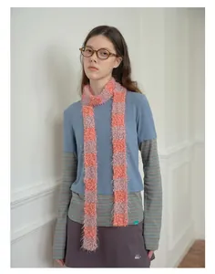 Detailed texture of pink and orange checkered plush scarf styled in a layered outfit