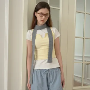Woman in casual white T-shirt and yellow knit vest with thin grey wool blend scarf