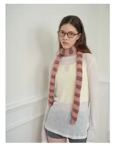 Dettaglio della sciarpa in maglia a righe rosa e marroni indossata dal modello con stile