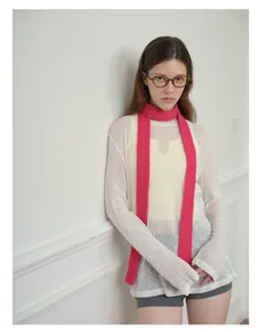 Dettaglio di una sciarpa in maglia magenta abbinata a un top trasparente e pantaloncini grigi