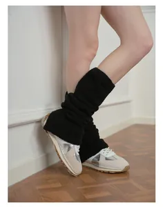 Dettaglio di scaldamuscoli neri in eco-pelliccia con spacco e sneakers argento massicce