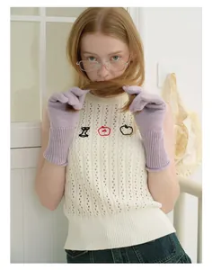 Detail of lavender wool knit gloves paired with ivory vest featuring apple embroidery