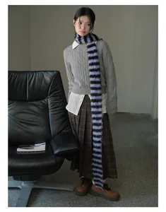 Detailed view of the purple and black striped faux fur scarf on a knit sweater outfit