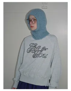 Detail of light blue fuzzy knitted balaclava hood worn with a grey graphic sweatshirt