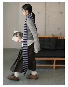 Detailed view of long faux mink fur striped scarf with retro cable knit sweater