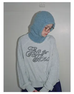 Detail of light blue knitted wool balaclava paired with a casual gray graphic sweatshirt