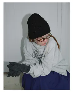 Detailed view of black knitted beanie and charcoal grey gloves for winter fashion